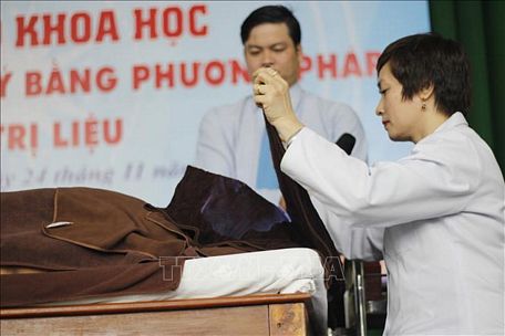  Bác sỹ Nguyễn Tuyết Mai, Viện Châm cứu Trung ương trình diễn hỏa trị liệu để điều trị bệnh. Ảnh: Đinh Hằng/TTXVN