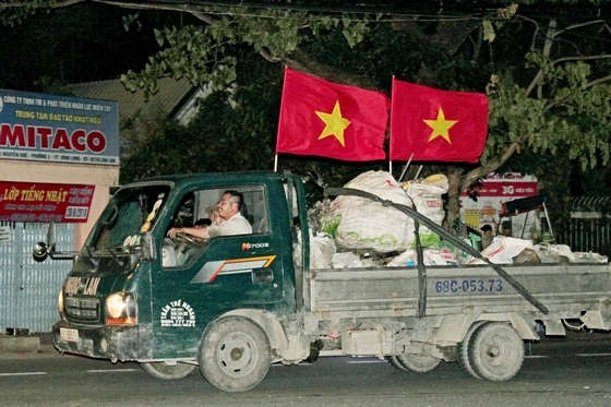 xe tải chở hàng hóa, gắn cờ Tổ quốc Việt Nam tung bay trên mọi nẻo đường, hòa cùng niềm vui chung của cả nước.