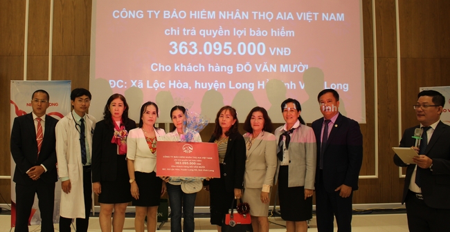 Đại diện công ty trao chi trả quyền lợi bảo hiểm cho khách hàng.