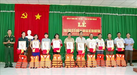 Lãnh đạo BĐBP Sóc Trăng trao tặng cờ và ảnh bác Hồ cho ngư dân vùng ven biển Sóc Trăng. 