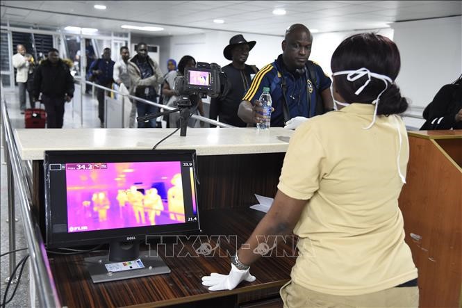  Nhân viên y tế kiểm tra thân nhiệt hành khách tại sân bay quốc tế Murtala Mohammed ở Lagos, Nigeria. Ảnh: AFP/TTXVN
