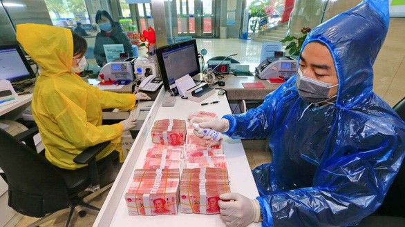 Một nhân viên đang tẩy uế các đồng bạc đã qua sử dụng tại trụ sở ngân hàng Toại Ninh (Tứ Xuyên, Trung Quốc) ngày 26-2-2020 - Ảnh: TELEGRAPH