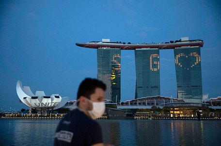 Một người đàn ông đi bộ trước khu nghỉ mát Marina Bay Sands, được thắp sáng tưởng nhớ các nhân viên y tế.