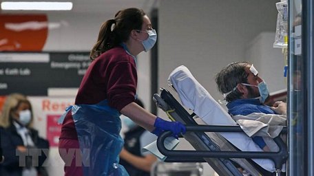 Nhân viên y tế chuyển bệnh nhân nhiễm COVID-19 tới bệnh viện ở London, Anh. (Ảnh: AFP/TTXVN)