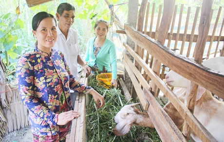 Chị Mai (đứng phía trước) được hỗ trợ sửa nhà, nuôi dê và vốn để làm kinh tế.