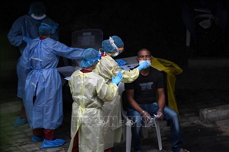 Nhân viên lấy mẫu xét nghiệm COVID-19 cho người lao động nước ngoài ở Singapore ngày 27/4. Ảnh: AFP/TTXVN