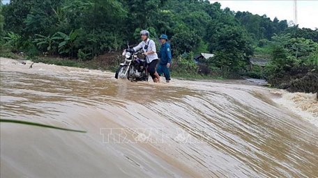 Công an xã giúp người dân qua ngầm tràn Tân Long, xã Cốc Mỳ, huyện Bát Xát (Lào Cai) đêm về sáng ngày 4/7. Ảnh: Hồng Ninh/TTXVN