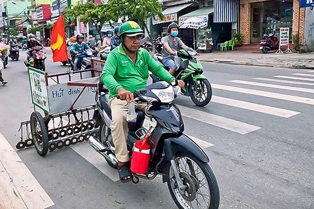 Ông Sáu Dựa chạy xe đi hút đinh trên đường.