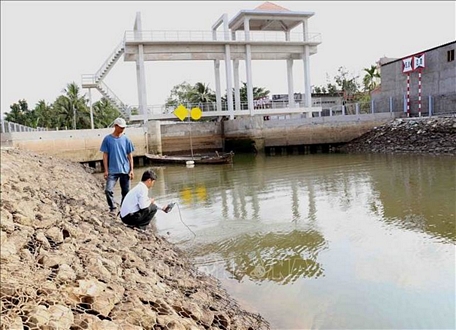 Cán bộ kỹ thuật của Sở Nông nghiệp và Phát triển nông thôn kiểm tra đo độ mặn tại cống thủy lợi Tre Bông, xã Tiên Thủy, huyện Châu Thành. Ảnh: Vũ Sinh/TTXVN