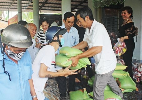 Người thân gia đình ông Nguyễn Văn Tư cùng địa phương phát quà cho hộ nghèo.