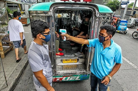 Kiểm tra thân nhiệt nhằm ngăn chặn sự lây lan của dịch COVID-19 tại Manila, Philippines. Ảnh: THX/TTXVN