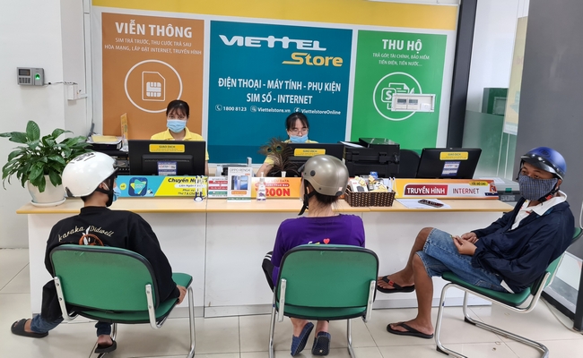 Tại các cửa hàng của Viettel, Vinmart,... đều có dịch vụ thu hộ điện, nước (ảnh trái) và nhiều người đang làm quen với hình thức thanh toán này tại một điểm giao dịch của Viettel (ảnh phải).