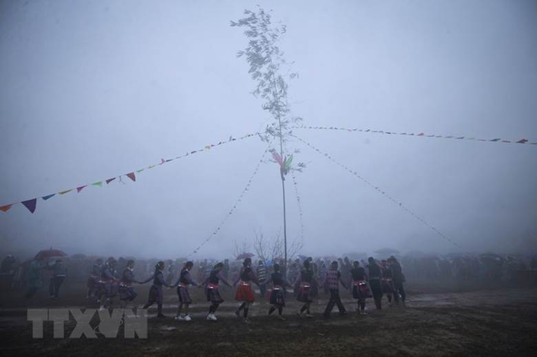  Các chàng trai, cô gái Mông cùng du khách nắm tay nhau nhảy múa theo tiếng khèn xung quanh cây nêu. (Ảnh: Trọng Đạt/TTXVN)