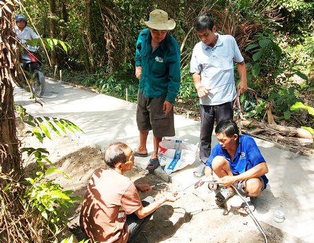 Nông dân xã Hiếu Nghĩa (Vũng Liêm) tham gia kéo điện thắp sáng trên các tuyến đường nông thôn.