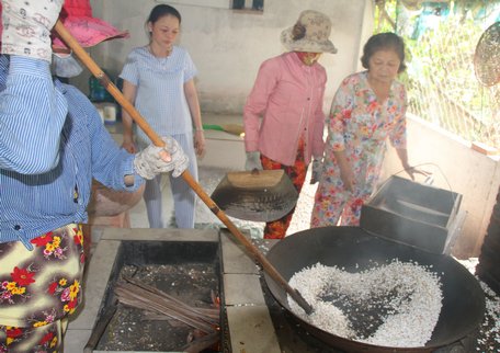 Khâu rang bông gạo theo lối truyền thống bằng chảo lá sen lớn cùng với cát sông.