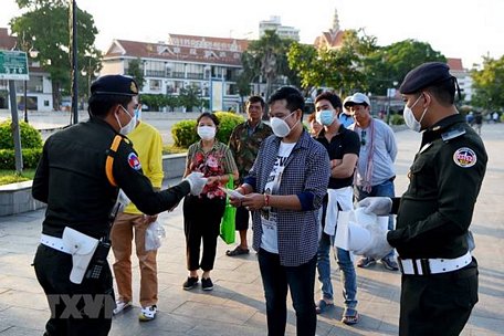 Cảnh sát phát khẩu trang cho người dân để phòng dịch COVID-19 tại Phnom Penh, Campuchia ngày 12/11/2020. (Ảnh: AFP/TTXVN)