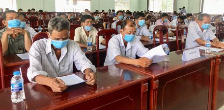 Người dân xã Loan Mỹ nghiên cứu tiểu sử người ứng cử tại buổi tiếp xúc cử tri, vận động bầu cử.