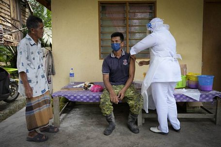  Một nhân viên y tế đang chuẩn bị tiêm vaccine Pfizer cho một nông dân ở bang Selangor. Ảnh: AP
