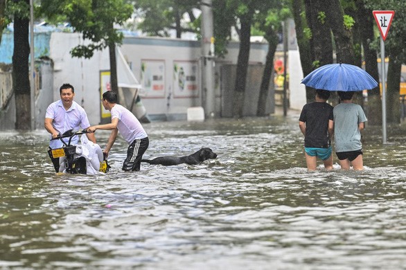 Người dân đi qua một con đường bị ngập nước ở thành phố Ninh Ba, tỉnh Chiết Giang ngày 25/7 khi bão In-Fa tấn công khu vực phía đông Trung Quốc - Ảnh: AFP