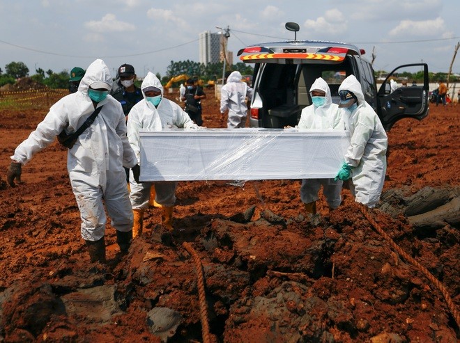 Nhân viên mặc đồ bảo hộ chôn cất nạn nhân Covid-19 tại Jakarta (Ảnh: Reuters).