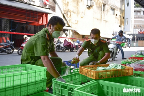 Thiếu tá Lê Đức Long và trung úy Nguyễn Minh Tiến (Công an phường Cầu Ông Lãnh, quận 1) chọn lựa rau củ cho người dân - Ảnh: NGỌC PHƯỢNG