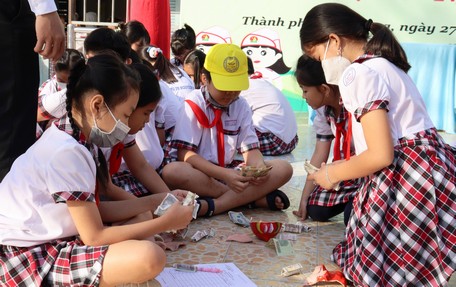 Thiếu nhi tham gia nuôi heo đất gây quỹ giúp bạn nghèo. 