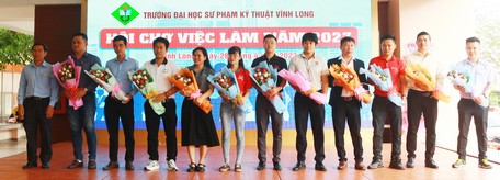 Lãnh đạo Trường ĐH Sư phạm kỹ thuật Vĩnh Long tặng hoa cho các doanh nghiệp, công ty tham gia ngày hội việc làm.